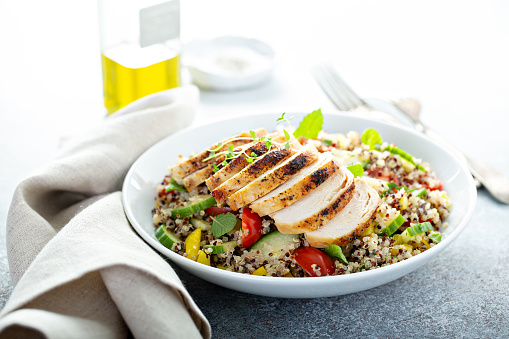 Fresh quinoa tabbouleh salad with grilled chicken, tomatoes and cucumbers, healthy lunch bowl