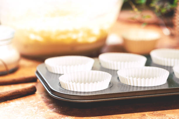 istock Muffin cups in muffin tin and a bowl with dough on the kitchen table 1194742411