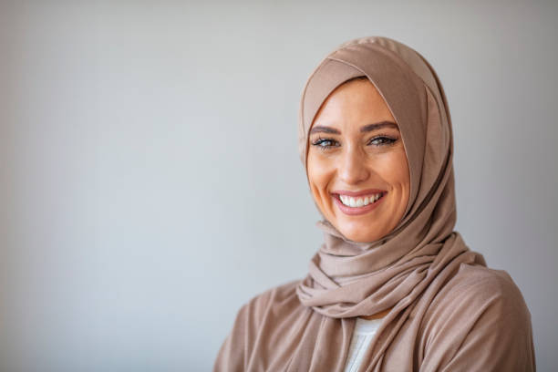 Smiling Muslim Woman Wearing Hijab Portrait of a young woman in traditional Muslim clothing, smiling. Beautiful woman headshot looking at camera and wearing a hijab. Arabian woman with happy smile. Strict formal outfit and elegant appearance. Islamic fashion. islam photos stock pictures, royalty-free photos & images