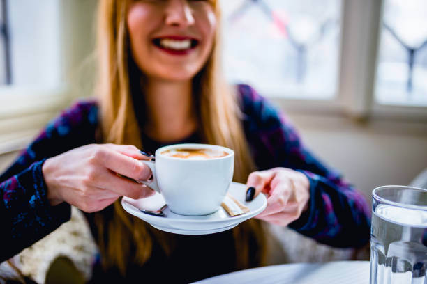 Happy young woman in a cafe sitting and drinking coffee