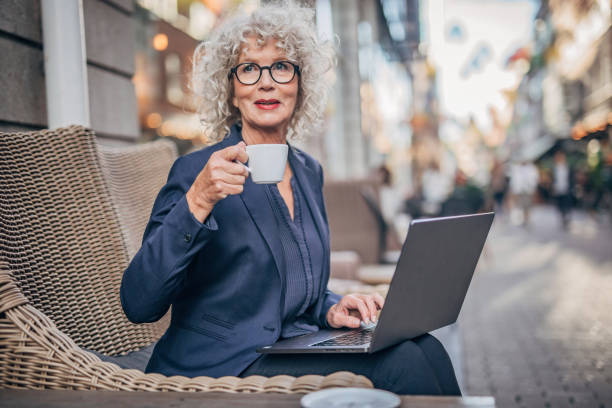 istock Beautiful senior woman working on laptop while drinking coffee 1194747962