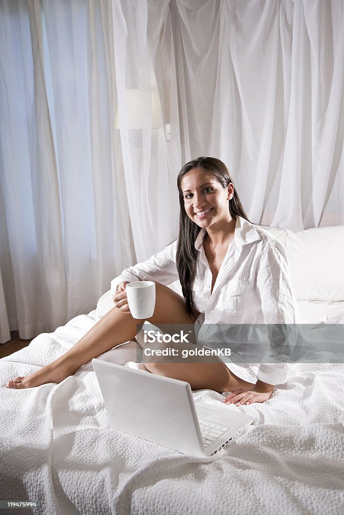 Hispanique femme assise sur le lit et boire du café - Photo de Lit à baldaquin libre de droits