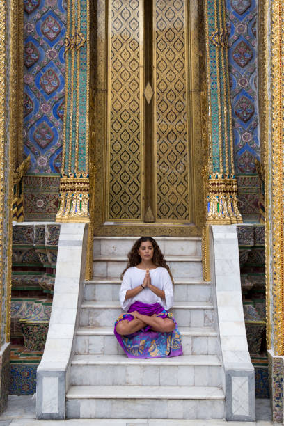 jeune femme, avec de longs cheveux bruns, visitant le grand palais, bangkok - zen like women temple meditating photos et images de collection