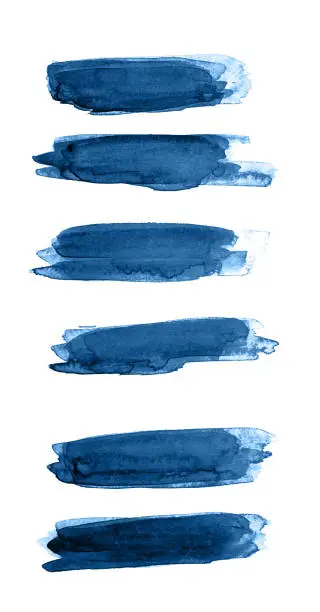 Photo of Classic blue color of year 2020 strokes of watercolor paint of different sizes on a white isolated background.