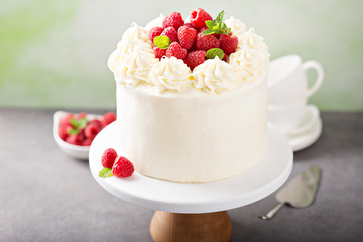 White chocolate raspberry cake on a cake stand