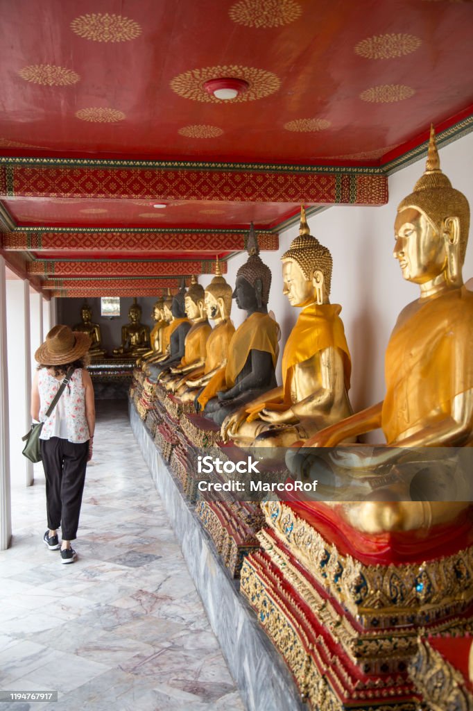 Woman With Curly Hair And Sun Hat Walking Next To Golden Buddha Statues At  Wat Pho Stock Photo - Download Image Now - iStock