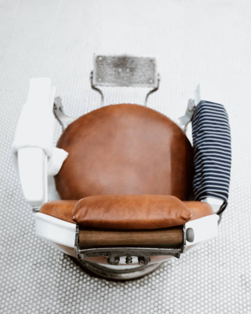 Old fashioned, retro style leather and metal barber chair with cape.