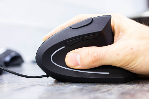man’s hand uses a vertical ergonomic computer mouse-joystick.