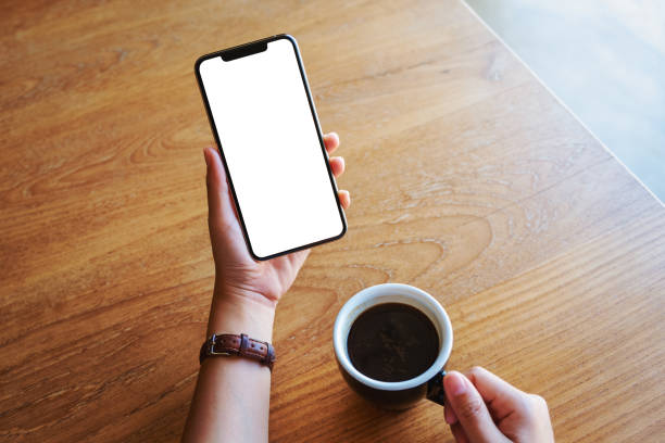 istock hands holding black mobile phone with blank screen with coffee cup on wooden table 1194779155