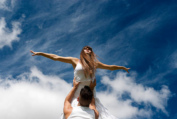young couple dancing on sky background, freedom and relax symbol stock photo