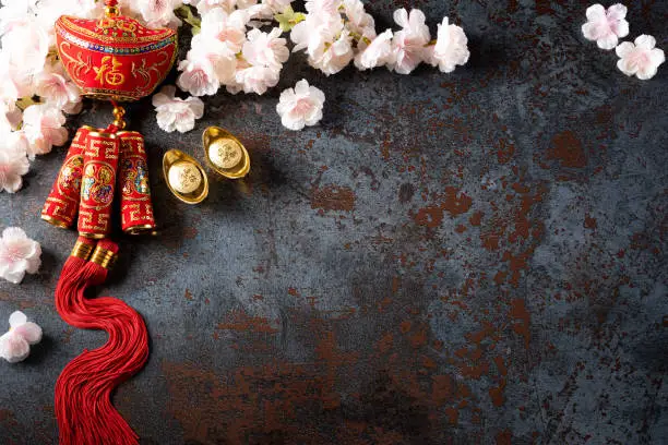 Chinese new year festival decorations pow or red packet, orange and gold ingots or golden lump on a black stone texture background. Chinese characters FU means fortune good luck, wealth, money flow.