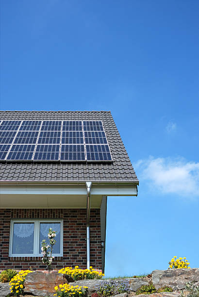 Solar panels on top of a brick house roof  Roof with solar panels and wind turbines aside solar power station solar panel house solar energy stock pictures, royalty-free photos & images