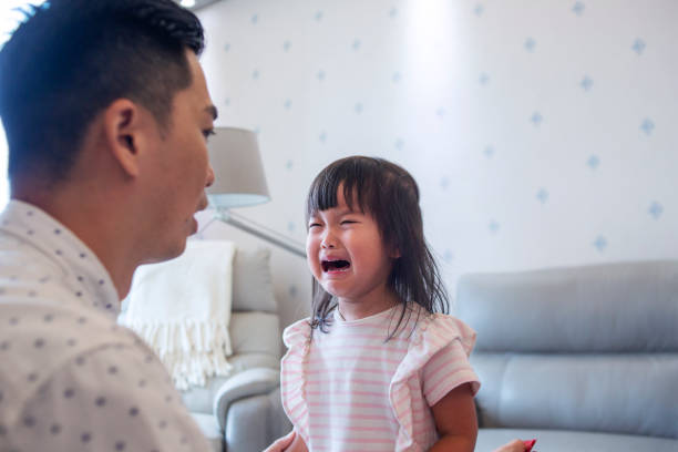 fermez-vous vers le haut du père asiatique consolant la fille pleurante - piquer une colère photos et images de collection