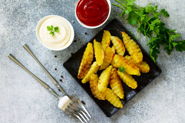 comida rápida. patatas al horno con especias, rodajas sobre pizarra o piedra, servidas con mayonesa y salsa de ketchup. vista superior sobre un fondo plano. - 18827 fotografías e imágenes de stock