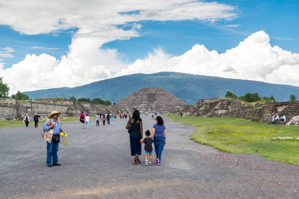 Tourist in the ruins of the architecturally significant Mesoamerican pyramids and green grassland located at at Teotihuacan, an ancient Mesoamerican city located in a sub-valley of the Valley of Mexico stock photo