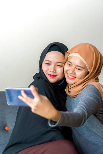 istock Two Malay friends wearing hijab at the sofa 1194801293