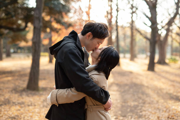istock Young couple kissing in park 1194802074