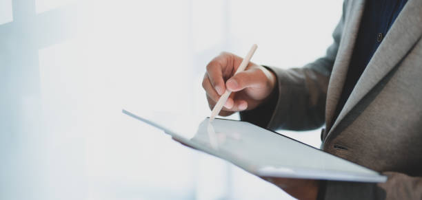 istock Close-up view of young businessmen working on his project while using tablet in modern office 1194812918