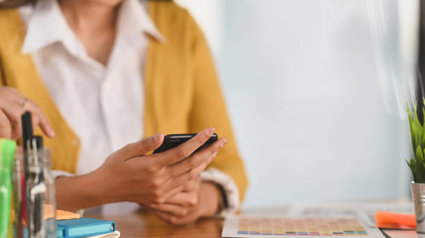 istock Closeup creative female using her smartphone on wooden desk. 1194812964