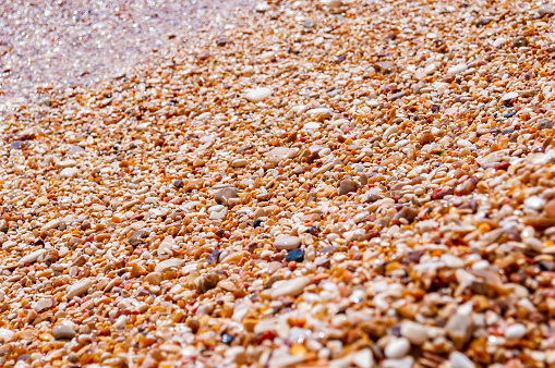 Coastal pebbles washed by Adriatic Sea water waves on Baia delle Zagare beach in Gargano National Park, Puglia, Italy