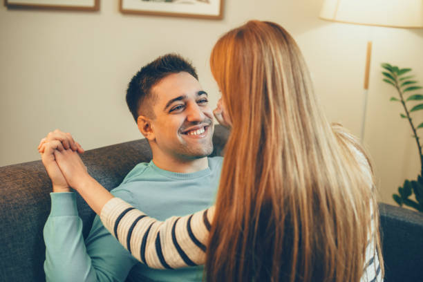 istock Young man laughing while having fun at couch at home with her girlfriend which is sitting on him. 1194816121