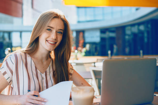 istock Beautiful business woman working outside writing in a notebook while looking at camera smiling . Red haired female freelancing outdoor. 1194816200