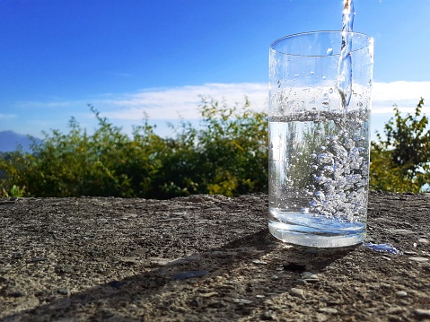 This is a picture of clean water pouring into a transparent glass taken in a natural background in a beautiful day and sunshine.