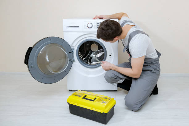 istock serviceman repairs broken washing machine near beige wall 1194819989