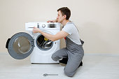 junger-servicemann-in-grauer-uniform-repariert-kaputte-waschmaschine.jpg?b=1&s=170x170&k=20&c=Dh6MP9H51bBcTRxxo4NvYxTTdDhM2wADZF56GWEuL6Y=