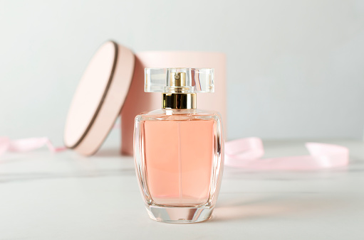 Primer plano de la botella de vidrio de perfume y la caja de regalo abierta como fondo en la superficie blanca photo
