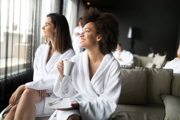 mujer relajarse y beber té en túnicas durante el bienestar - bathrobe women cup towel fotografías e imágenes de stock