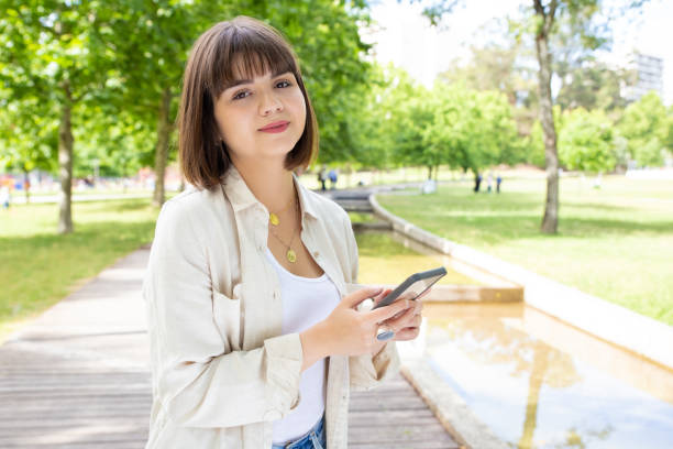 istock Beautiful smiling woman using smartphone in park 1194828792