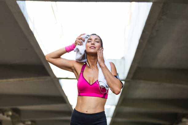 istock Young smiling female resting after an active fitness training while standing against gray wall with copy space area for your text message, satisfied fit woman resting after an active fitness training 1194828898