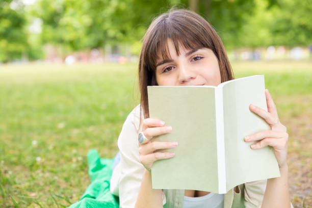 istock Young woman reading book in park 1194829144