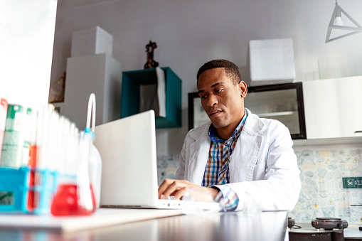 African-American Male scientist working in the laboratory with laptop computer and liquid chemical
