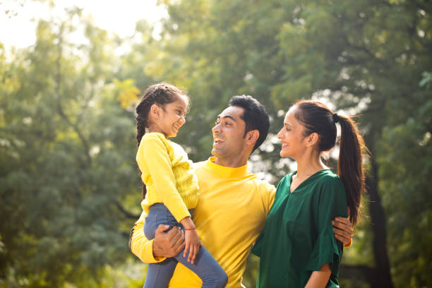 istock Happy parents holding daughter at park 1194829989