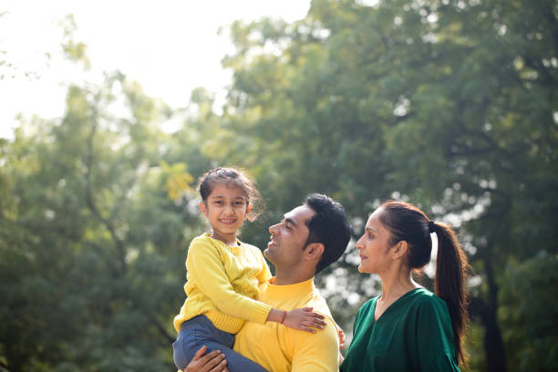 istock Happy parents holding daughter at park 1194830039