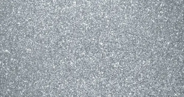 Photo of Silver glitter background, sparkling shimmer glow particles texture. Silver light sparks and glittering foil sequins background with shine sparks glare