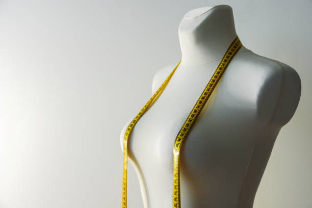 Tailor dummy with measuring tape Tailor mannequin with yellow measuring tape on grey background fashion designer stock pictures, royalty-free photos & images