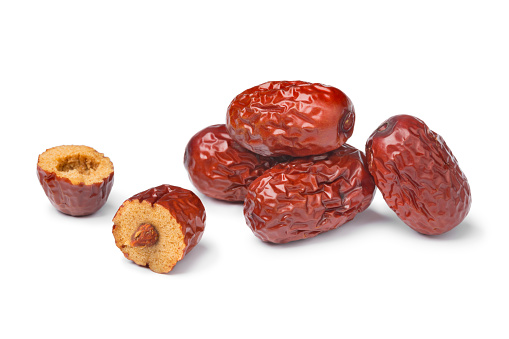 Heap of whole dried Chinese red dates and a halved one solated on white background