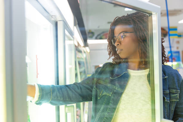 istock Young female customer taking food from fridge shelf 1194840591