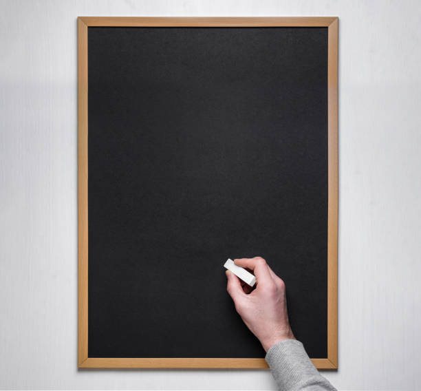 istock Male hand with chalk on the empty blackboard or chalkboard. 1194843424