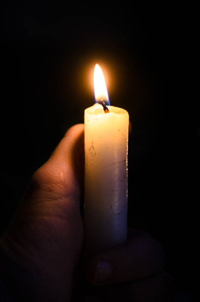 istock Candle in hand on a black background with a clear wick 1194845884