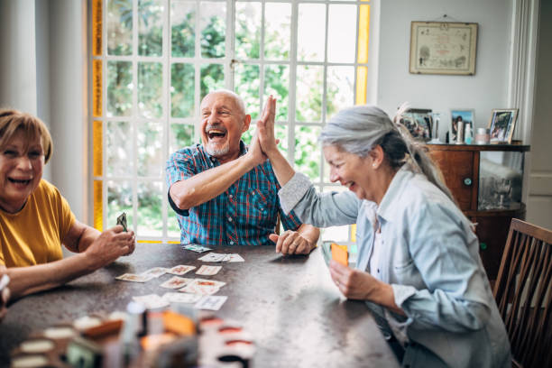 personas mayores jugando a las cartas en el hogar de ancianos - viejo fotografías e imágenes de stock