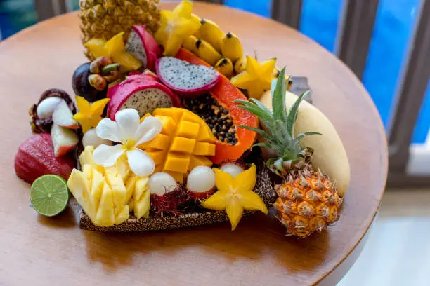 Photo of Juicy ripe tropical Thai fruits on a wooden dish.