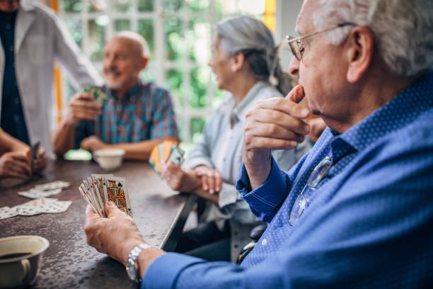 istock Senior gentleman playing cards with friends 1194850150