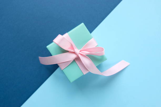 istock Blue gift tied with pink ribbon on blue background 1194851880