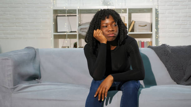 istock bored black girl sits on grey sofa against white wall 1194851994
