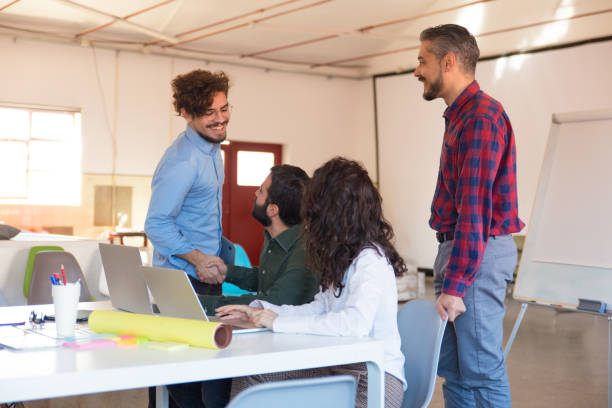 istock Positive startup team with laptops chatting in meeting room 1194856021
