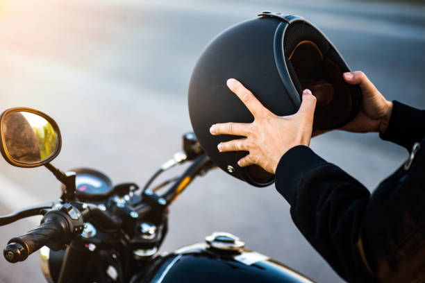 pareja de motocicletas sosteniendo cascos en las manos. - accesorio de cabeza fotos fotografías e imágenes de stock